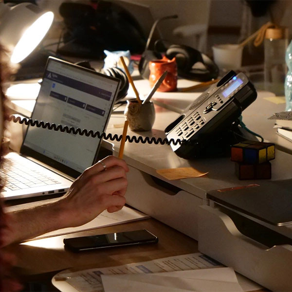 Photographie d’une personne assise à un bureau, de dos, répondant au téléphone de la ligne d’écoute, avec son ordinateur devant elle. L’ambiance est tamisée.
