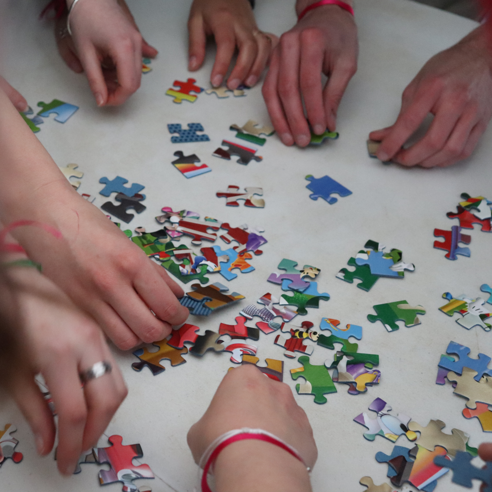 mains de bénévoles assemblant un puzzle